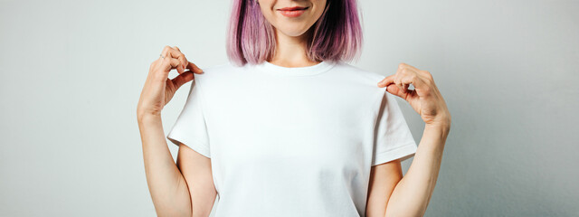 Pretty plus size model with white blank t-shirt and pink hear, empty grunge wall background. Holding her shirt and smiling, no face - obrazy, fototapety, plakaty