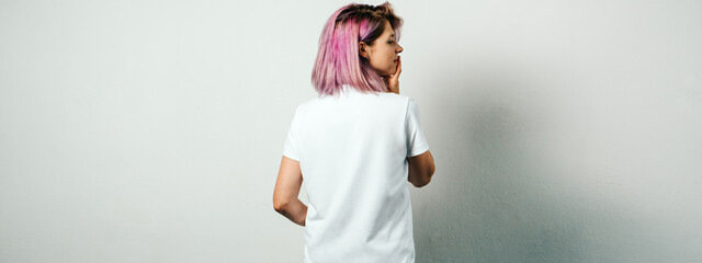 Pretty plus size model with white blank t-shirt and pink hear, empty grunge wall background. Back...