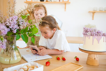 Little girls play in the kitchen and eat sweets.