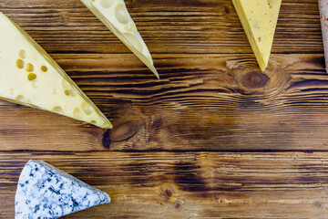 Various types of cheese on a wooden background. Top view