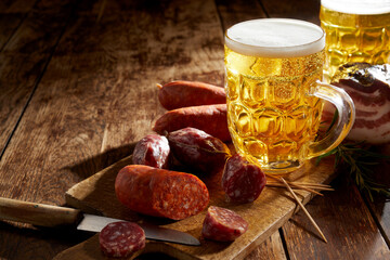Tankard of refreshing cold beer with spicy sausage