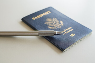 a blue passport with a pen on a desk