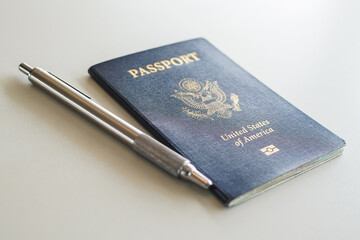 a blue passport with a pen on a desk