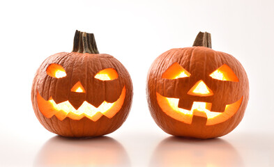 Two carved illuminated halloween pumpkins reflected on white table isolated