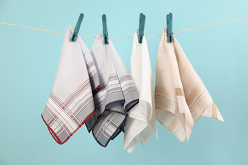 Many different handkerchiefs hanging on rope against light blue background - obrazy, fototapety, plakaty