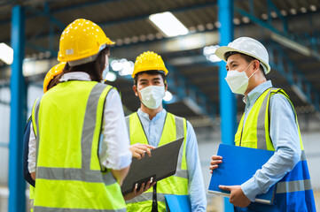 The factory employee consists of engineers, foreman, technicians, and related department staff. Wear a mask, hard hat, and vest. meeting before starting work inside the warehouse. Teamwork concept.