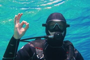 Man scuba diver underwater showing signal OK