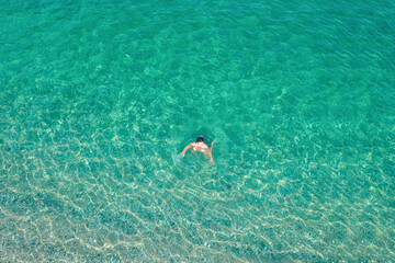 Young woman in a bikini swimming in sea water on the beach. View from above. Top, drone view