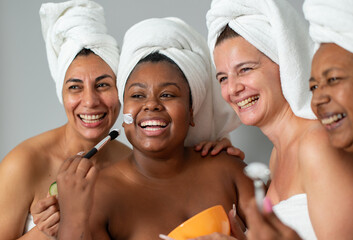 Cheerful diverse women applying mask together