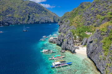 Beautiful coral reef, boats and a clear ocean on Matinloc Island, Bacuit Archipelago, El Nido, Palawan, Philippines. Aerial drone view.