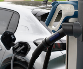 Electric car e-car on charge at public charger showing two different charge connectors in the foreground