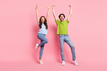 Full body photo of positive cheerful happy man and woman raise hands winner isolated on pink color...