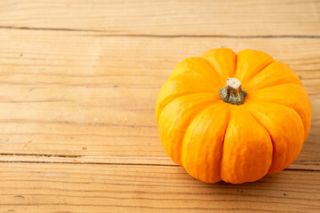 Top view of an orange pumpkin on rustic wooden table, horizontal, with copy space