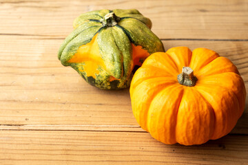 Close-up of two orange and green pumpkins on rustic wooden table, horizontal, with copy space