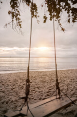 an empty wooden swing on the seashore of the Baltic Sea during cloudy weather