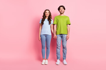 Full length photo of cheerful woman and man hold hands couple smile enjoy isolated on pink color background