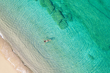 Young woman in a swimsuit swimming in sea water on the beach. View from above. Top, drone view