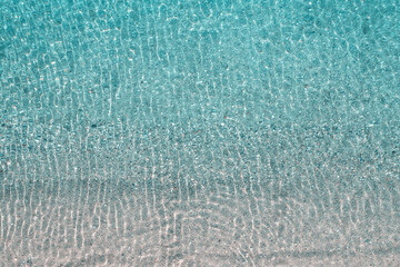 Blue, turquoise transparent water surface of ocean, sea, lagoon. Horizontal background. Top view of sand beach. Aerial, drone view