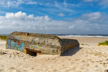 Fototapeta na wymiar Word War II bunker stained by graffiti and submerged in sand on Nymindegab Beach. South West Jutland, Denmark, Europe