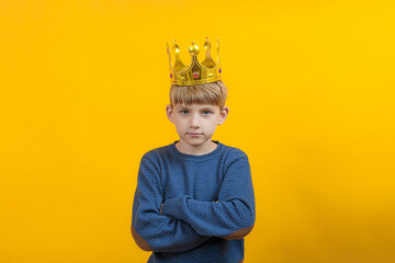 Boy in a blue sweater with a gold crown on a yellow background.