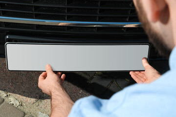 Man installing vehicle registration plate outdoors, closeup