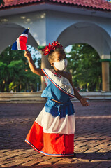 Niña Dominicana levantando la bandera hacia el cielo 