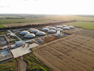 Aerial footage of biogas plant. Aerial view over biogas plant and farm in green fields