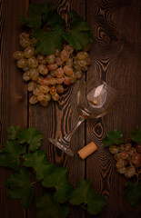 Bunch of pink grapes, with a wine glass, on a wooden table, food concept, top view, no people, vertical, rustic, toned,