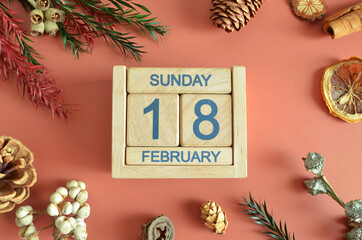 February 18, Cover design with calendar cube, pine cones and dried fruit in the natural concept.