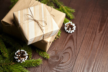 Gift boxes with green Christmas tree branch and cones on wooden background