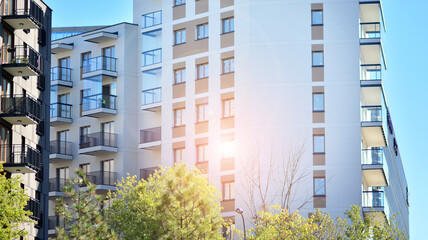 Inspiring view of the modern city. The wall of the apartment building   against trees. Apartment construction and ecology, view of  modern  building with blue sky and green tree. Sunlight