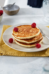 Pancakes for breakfast with sour cream, raspberry jam and fresh raspberries.