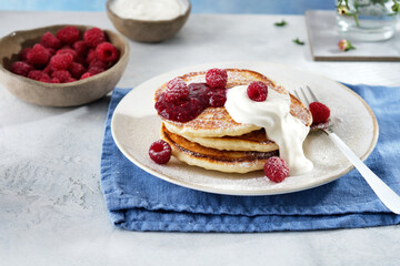 Pancakes for breakfast with sour cream, raspberry jam and fresh raspberries.
