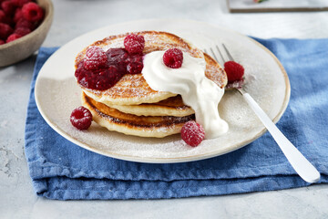 Pancakes for breakfast with sour cream, raspberry jam and fresh raspberries.