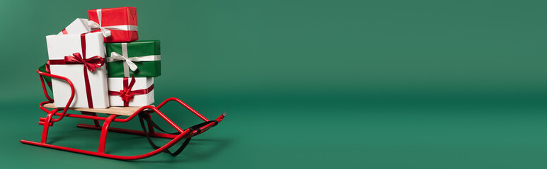 Presents with ribbons and bows on sleigh on green background, banner