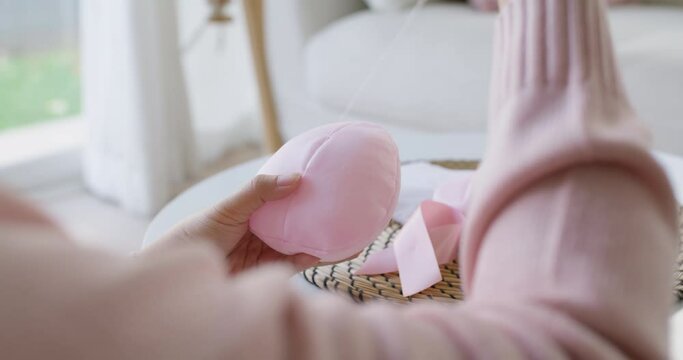 Close-up hand asia woman help make craft pink single fill up bra cup insert for post mastectomy prosthesis surgery MRM at home. Relief work service support give hope to tumor patient medical issue.