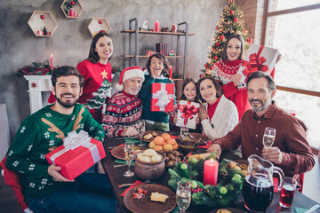 Photo portrait full family in decorated apartment receiving festive gift boxes from santa claus sitting at table