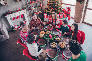 Photo portrait family praying together on xmas holding hands sitting at table before dinner in apartment