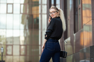 Young blonde woman talking on the phone in urban location. Lifestyle