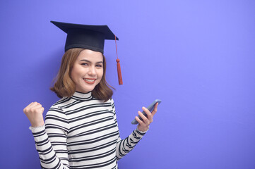 Portrait of young woman graduated over blue background