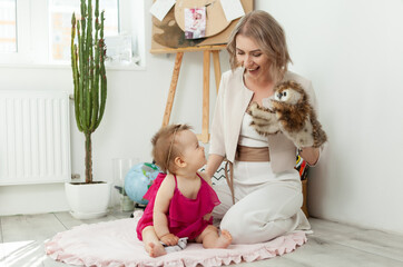 Happy loving family. Mother and little daughter in the children's room. Cute mom and lovely baby have fun and play with owl puppet