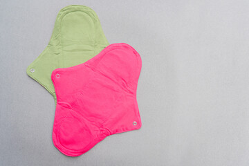 Cloth sanitary pads that are reusable, biodegradable and eco friendly. A pair of sanitary pads against grey background with copy space