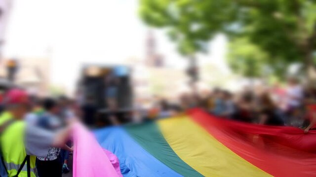 Unrecognizable people waving large LGBT flag on streets during gay pride at Lesbian Gay Bisexual Transgender LGBT visibility march pride Festigays  