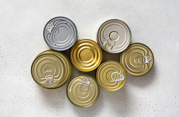 Various tin cans for food preservation on gray concrete background top view. Different canned food in steel cans. Conservation food, donation concept.