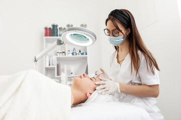 Cosmetologist does injections for anti wrinkle of beautiful woman. Women's cosmetology in beauty...