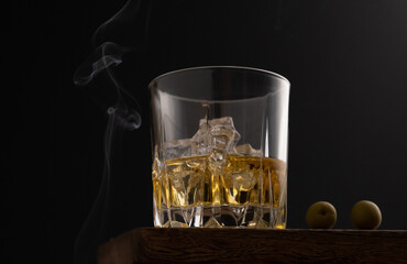 A glass of whiskey with olives and smoke
