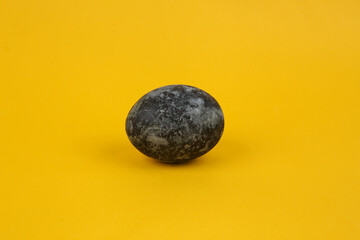 Gray marble painted Easter egg on yellow background