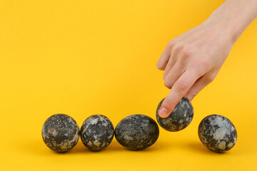 Hand picks Gray marble painted Easter eggs on yellow background