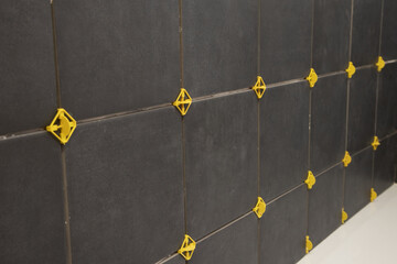 Pose d'un carrelage mural noir dans une salle de bains © hcast