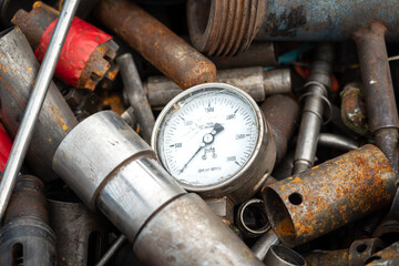 Broken pressure gauge or manometer which is junked on rusty metal scrap in junkyard. Industrial and electronic waste object photo.